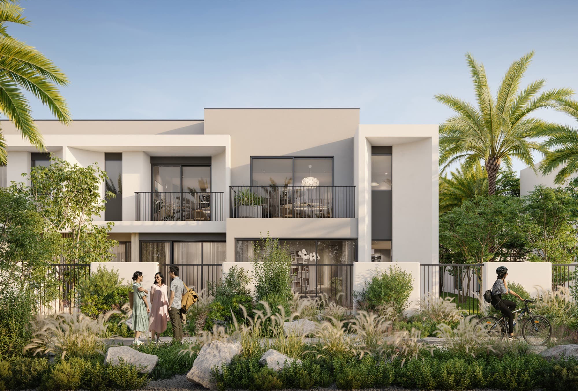 Daytime street view of Anya townhouses in Arabian Ranches 3, Dubai, with residents chatting and a cyclist passing by.