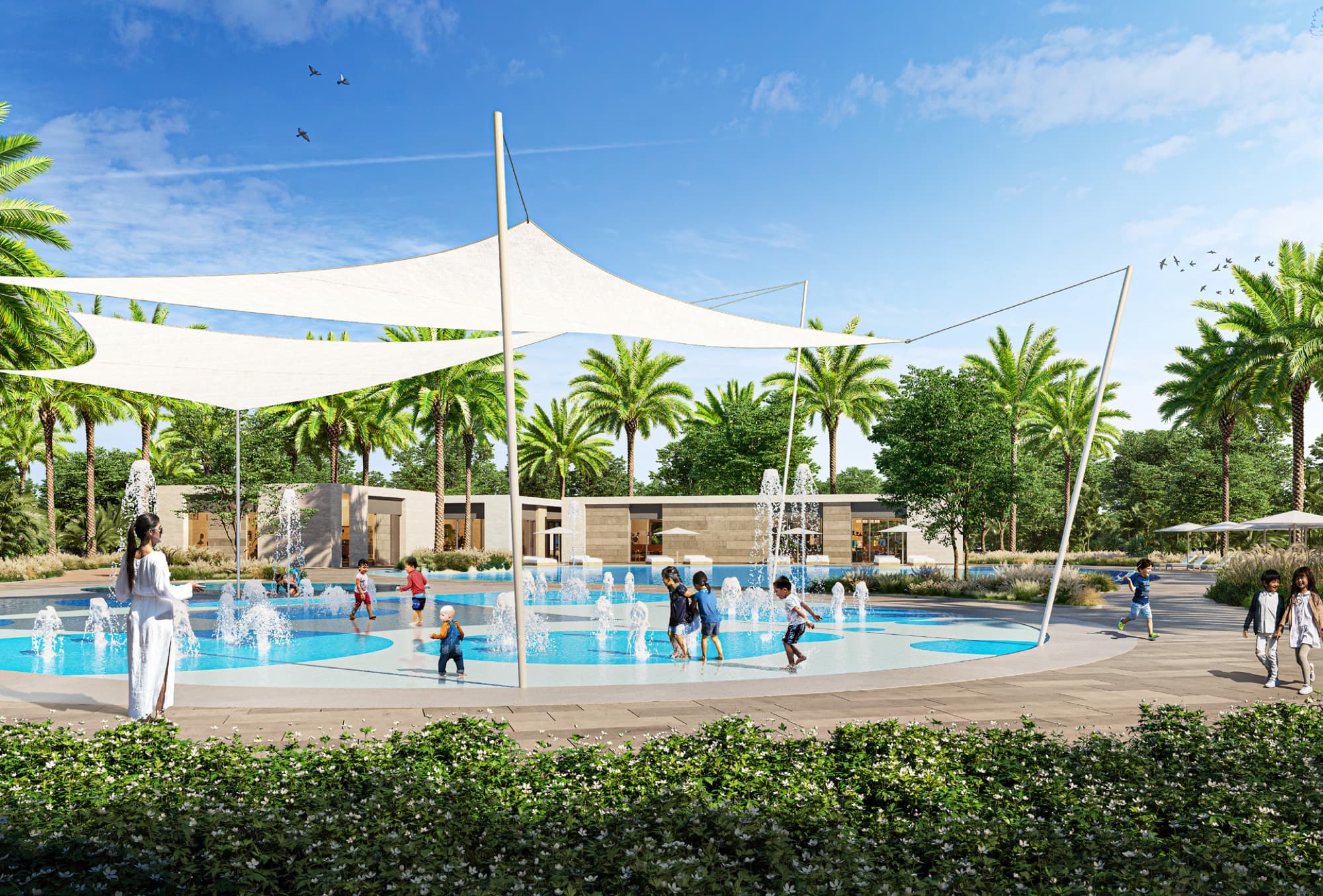 Children’s splash pad with shade sails at Anya, Arabian Ranches 3, families cooling off among palm trees.