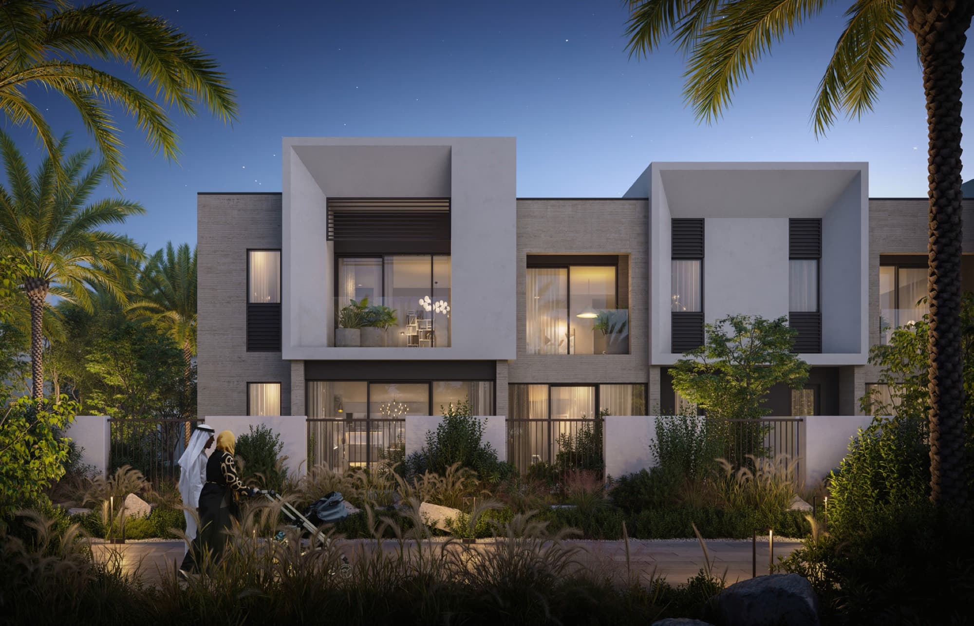 Dusk view of Anya 2 townhouses in Arabian Ranches 3, beige stone façade with residents walking a pram along the path.