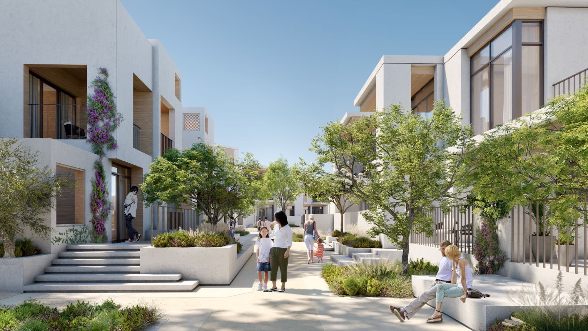 Residents walking a shaded pedestrian path lined with flowering shrubs between Bliss townhouses in Arabian Ranches 3, Dubai.