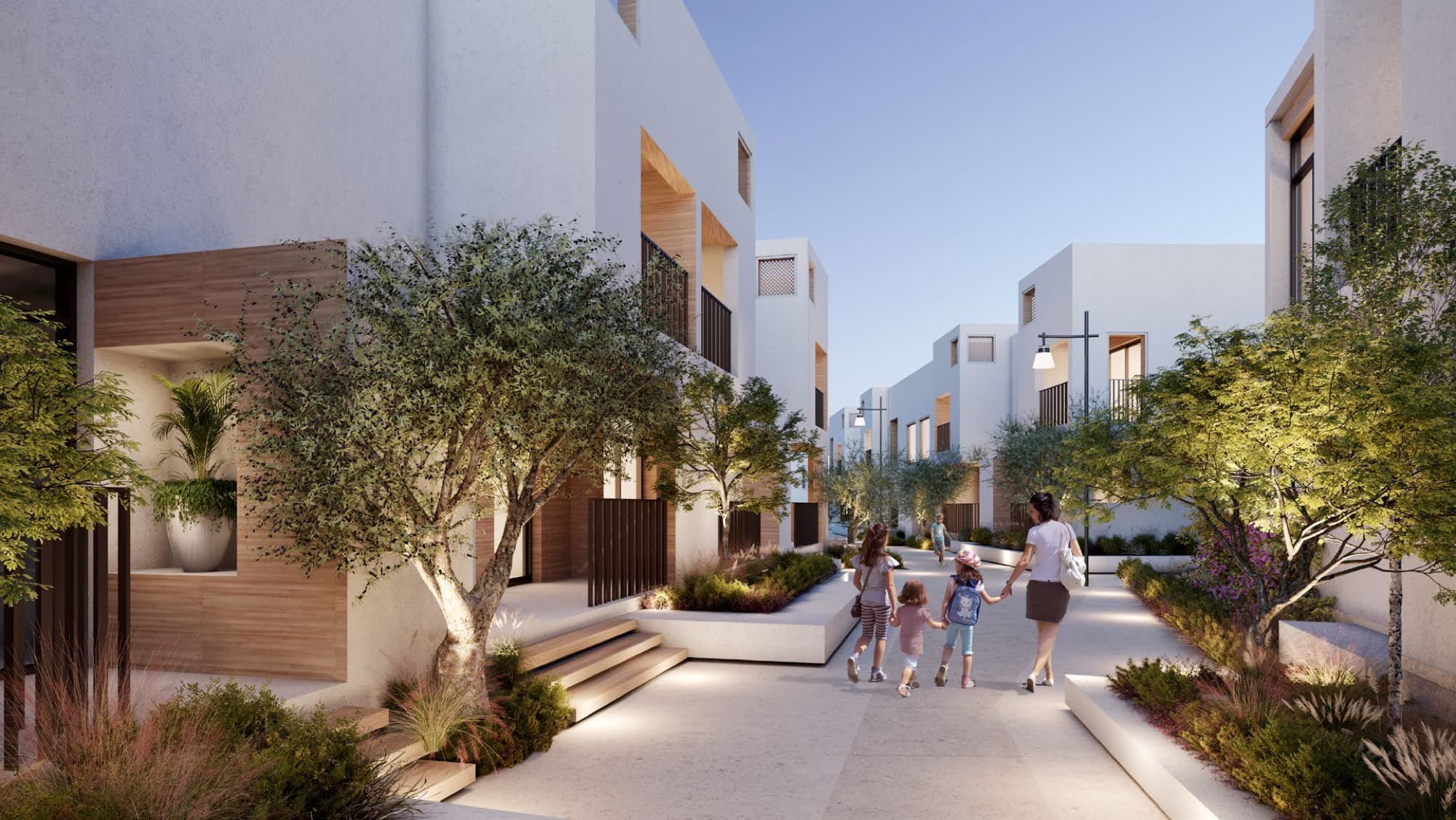 Evening view of Bliss townhouses in Arabian Ranches 3, Dubai, with residents on balconies overlooking a lit landscaped canal walkway.