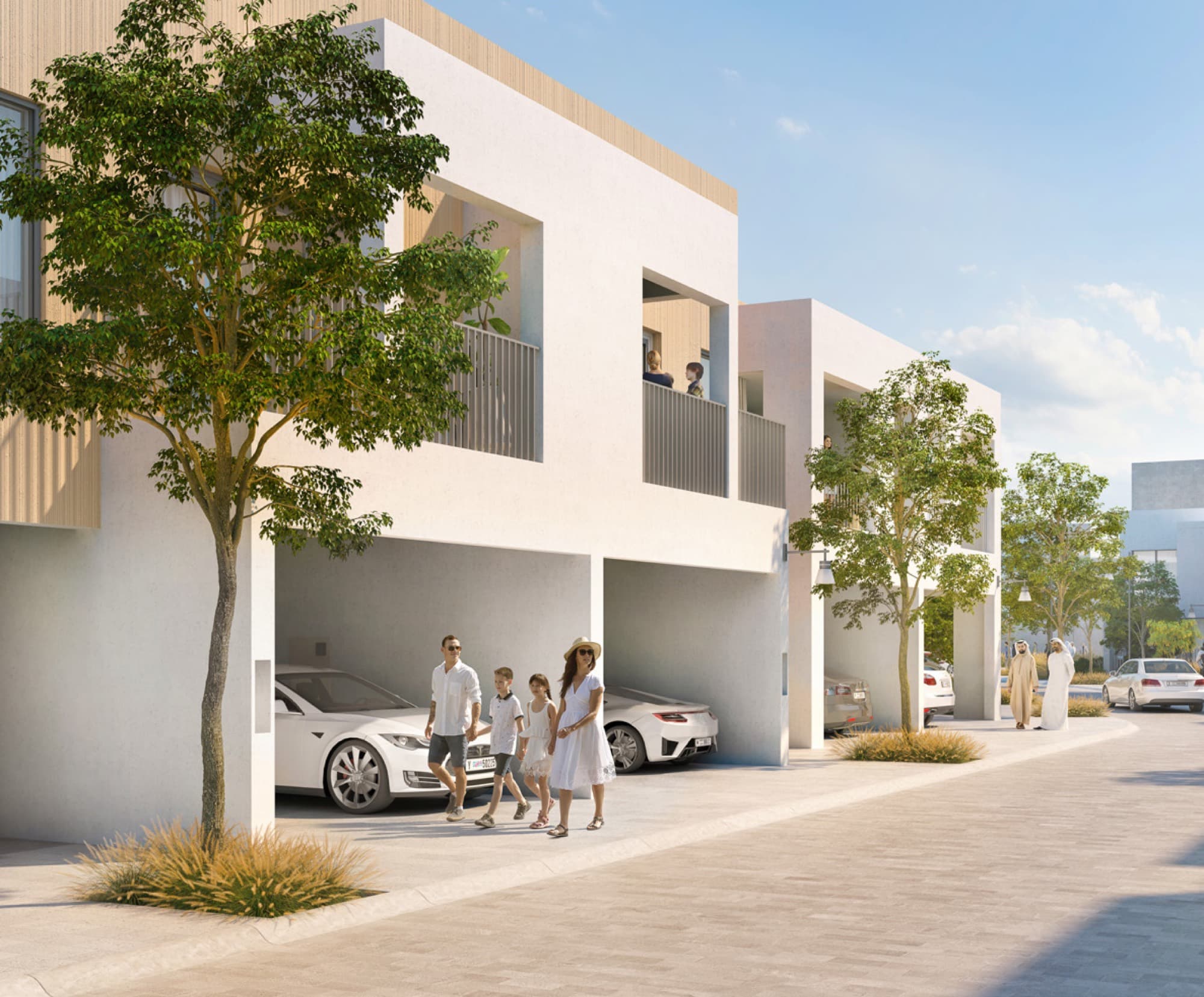 Family walking past covered garages of Bliss 2 townhouses in Arabian Ranches 3, Dubai, with residents chatting on the street.