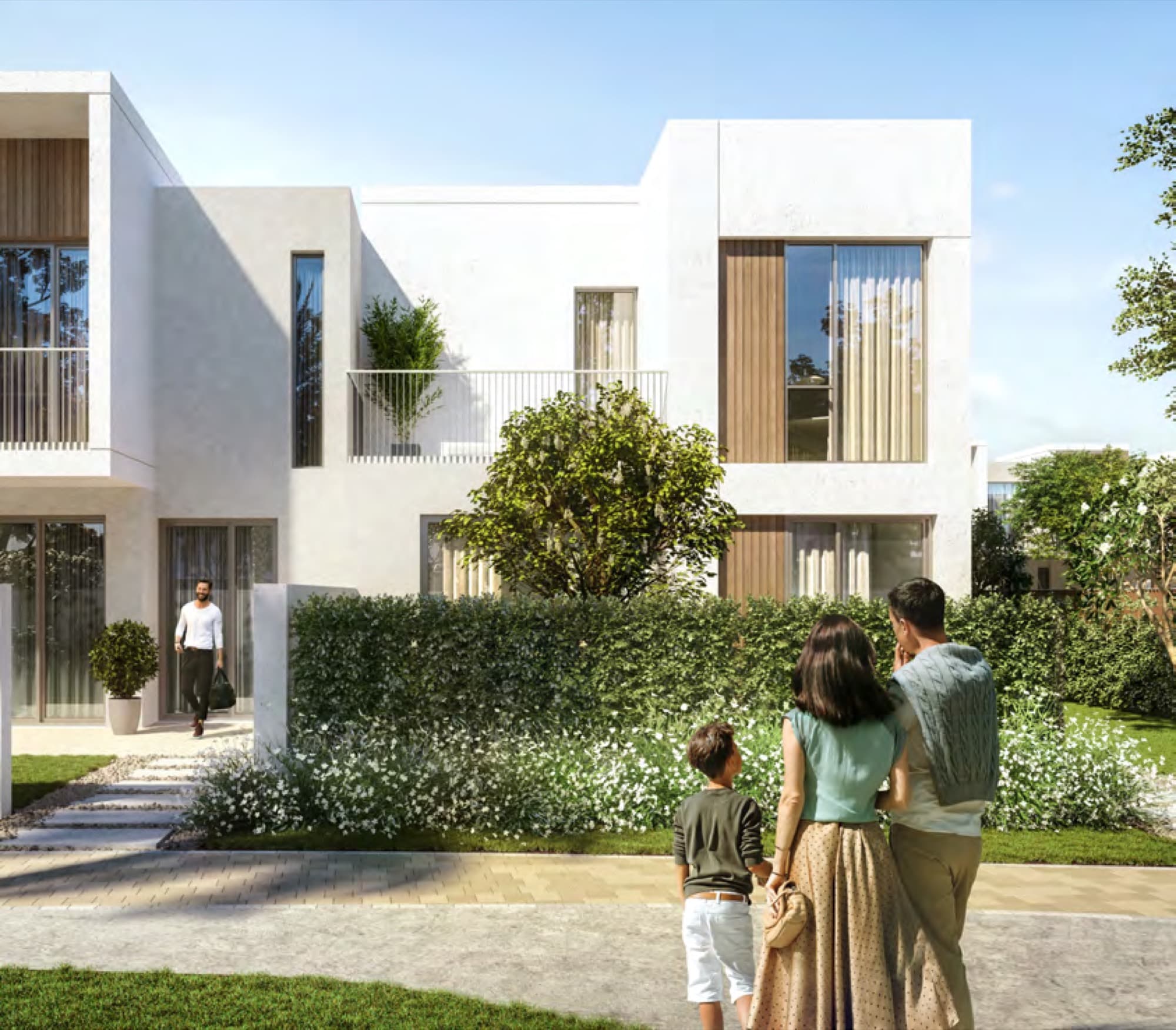 Family standing outside a Spring townhouse with landscaped hedges and pathway, Arabian Ranches 3, Dubai.